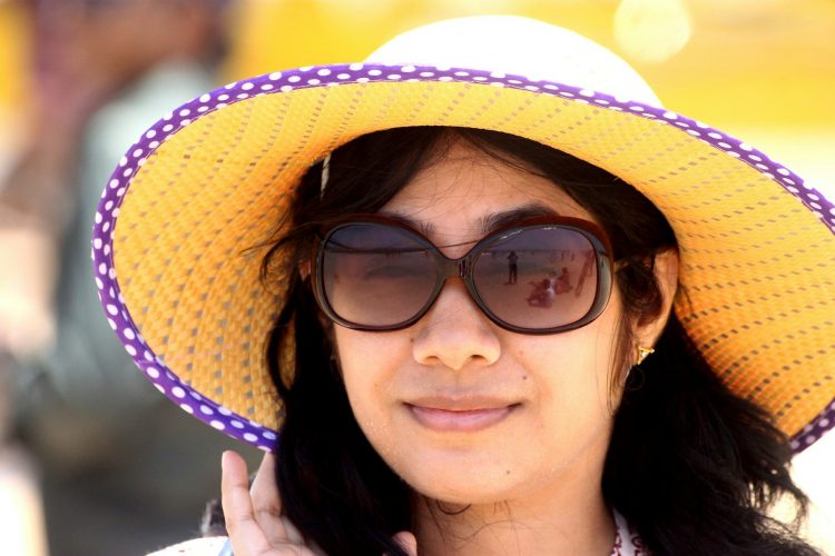 Augengesundheit im Sommer steigern durch den optimalen Schutz eines Sommerhutes wie die Frau mit Sonnenbrille
