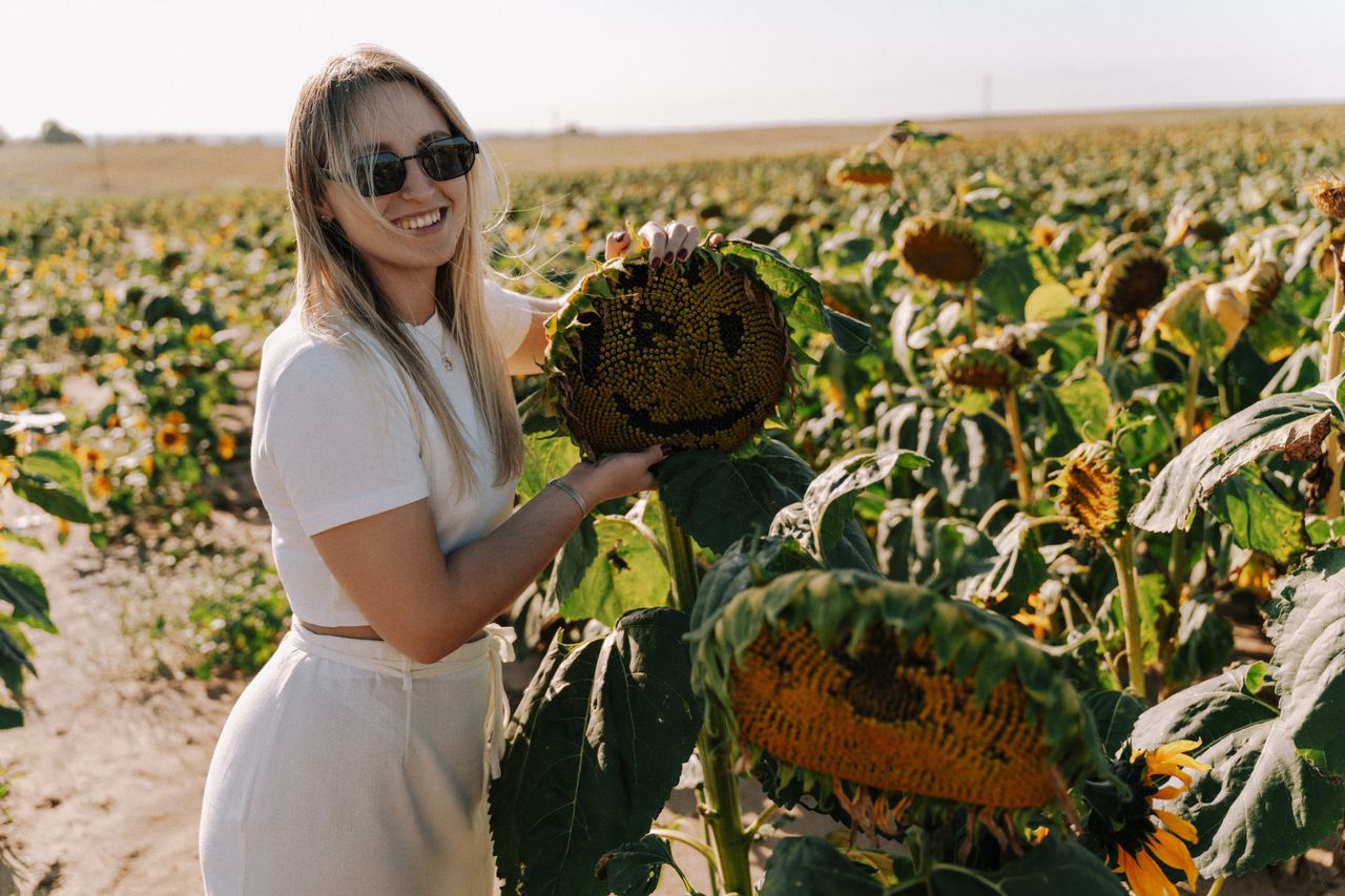 pexels-photo-33762630-33762630 Brille oder Kontaktlinsen - Frau mit Sonnenbrille auf dem Sonnenblumen Feld