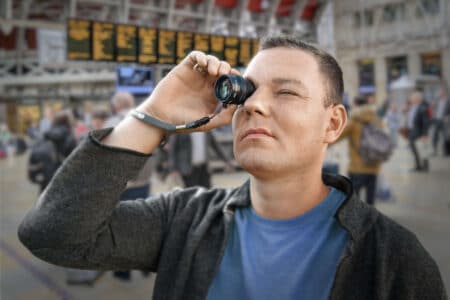 Mann mit vergrößender Lupe am Flughafen - er hat Altersbedingte Makuladegeneration
